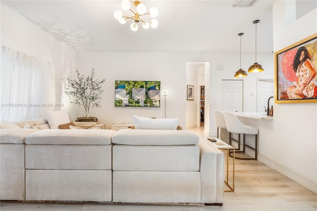 living room featuring visible vents, baseboards, light wood-style flooring, and a notable chandelier