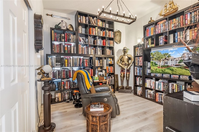 interior space featuring wall of books, a chandelier, and wood finished floors