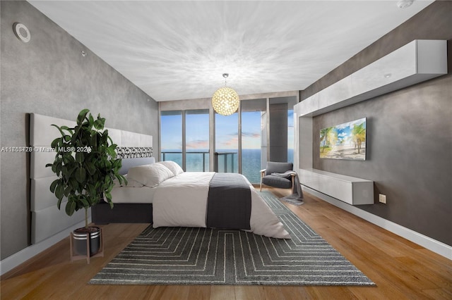 bedroom featuring expansive windows, baseboards, and wood finished floors