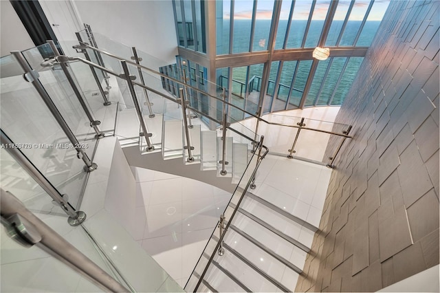 staircase featuring a water view and a towering ceiling