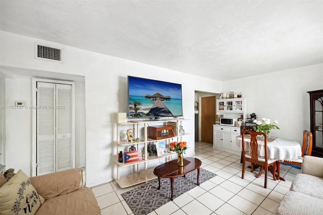 living area with light tile patterned floors, visible vents, and a textured ceiling