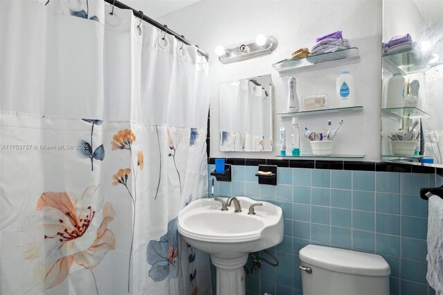 bathroom with toilet, tile walls, and a shower with shower curtain