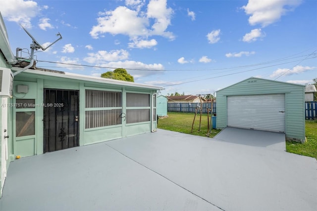 view of patio / terrace with concrete driveway, a detached garage, fence, and an outdoor structure