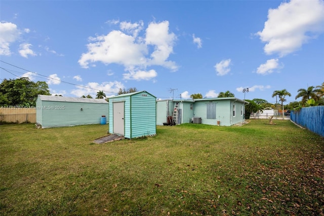 back of house featuring a storage shed, a lawn, an outbuilding, and fence