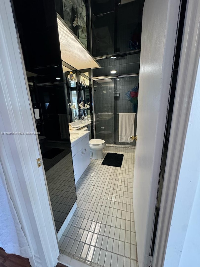 full bath with toilet, a stall shower, vanity, and tile patterned floors