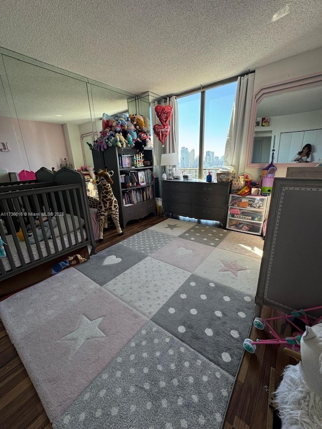 bedroom featuring a view of city, a textured ceiling, and wood finished floors