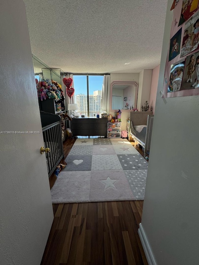 corridor featuring a view of city, a textured ceiling, wood finished floors, and a textured wall