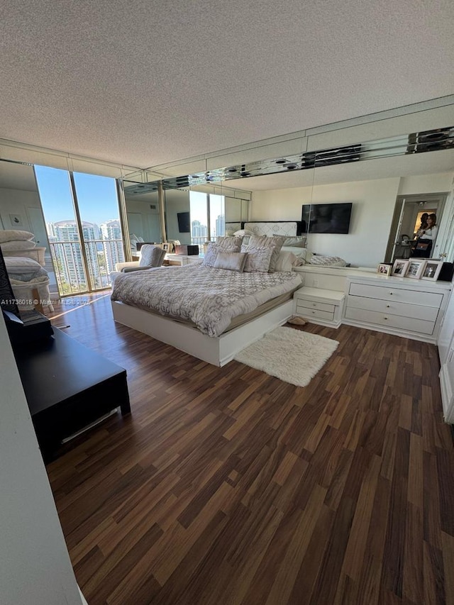 unfurnished bedroom with a wall of windows, access to outside, a textured ceiling, and dark wood-style floors