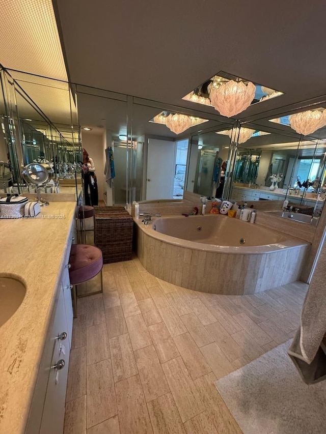 bathroom with vanity, a tub with jets, and wood finished floors