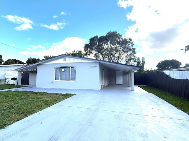 ranch-style house featuring driveway, an attached carport, a front yard, and fence