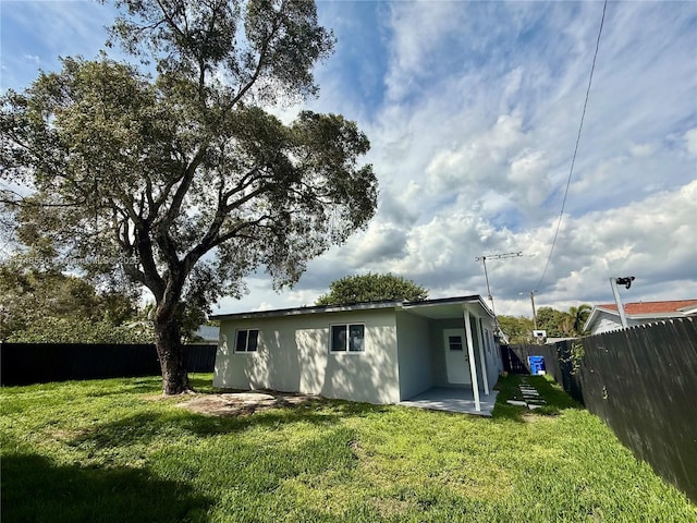 back of house with a fenced backyard, a patio, a lawn, and stucco siding