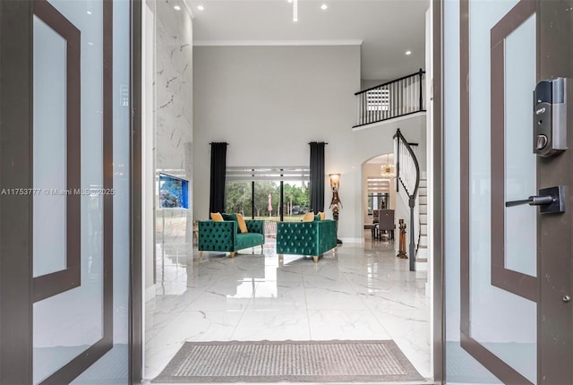 interior space featuring arched walkways, a high ceiling, marble finish floor, stairway, and crown molding