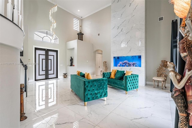 entryway with arched walkways, marble finish floor, ornamental molding, and visible vents