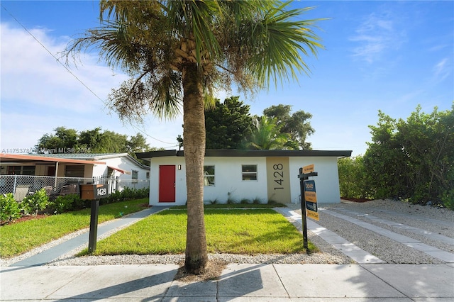 view of front of home with fence, a front lawn, and stucco siding