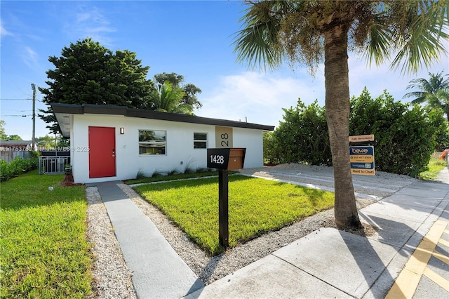 view of front of house with central air condition unit, a front lawn, and stucco siding