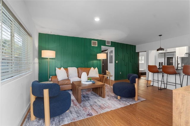 living area featuring recessed lighting, visible vents, wood finished floors, and an accent wall