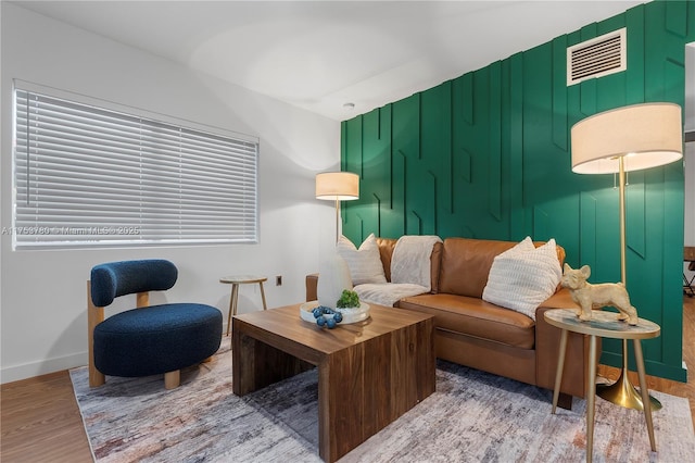 living room with wood finished floors, visible vents, and baseboards