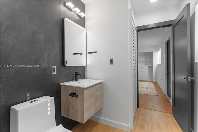 bathroom with baseboards, toilet, wood finished floors, and vanity