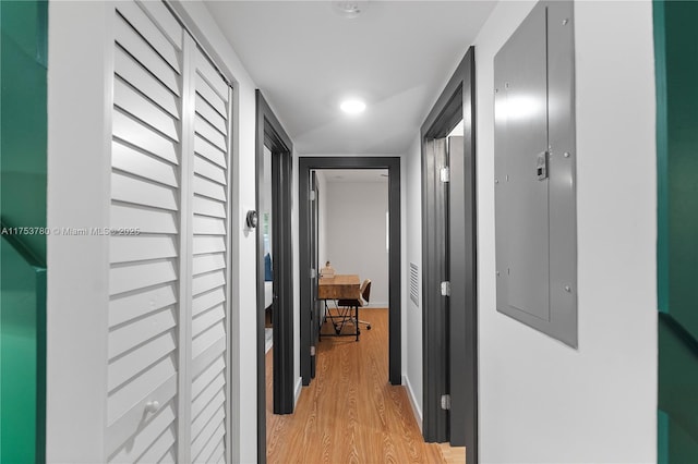 hall featuring electric panel, baseboards, and light wood finished floors