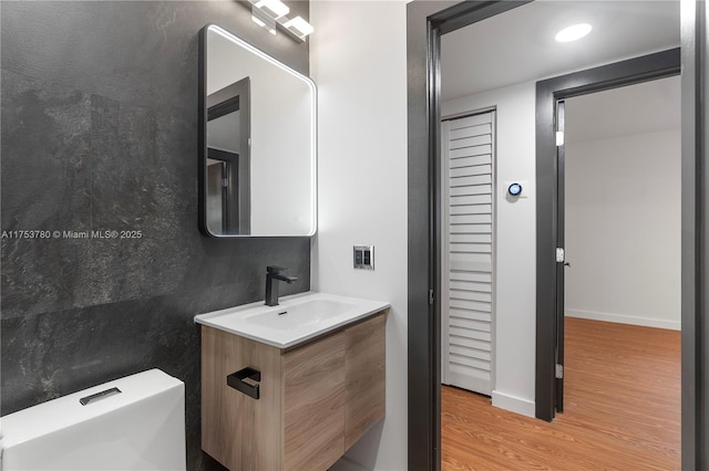 half bath featuring vanity, wood finished floors, and baseboards