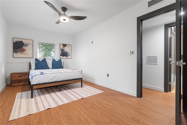 bedroom featuring light wood finished floors, visible vents, and baseboards