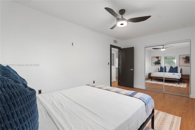 bedroom with a ceiling fan, wood finished floors, visible vents, and baseboards