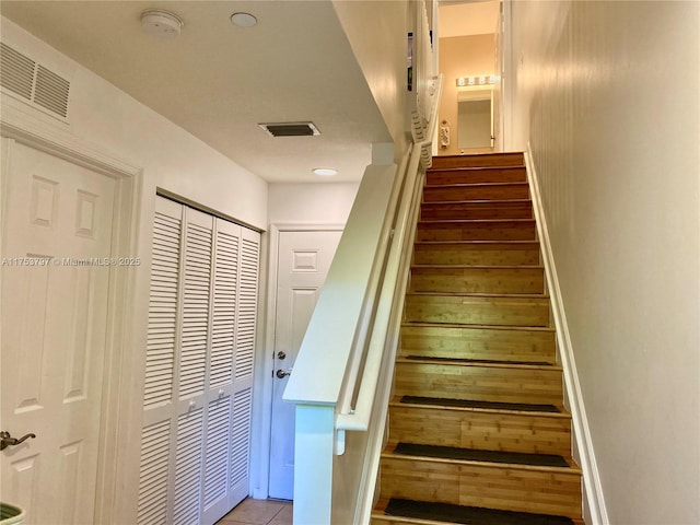 stairs with tile patterned flooring, visible vents, and baseboards