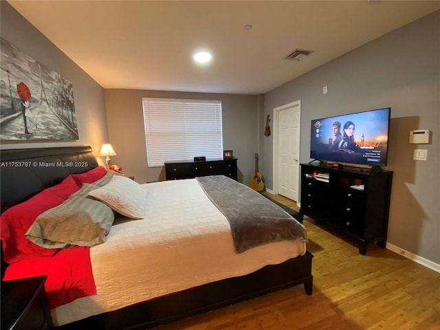 bedroom with visible vents, baseboards, and wood finished floors