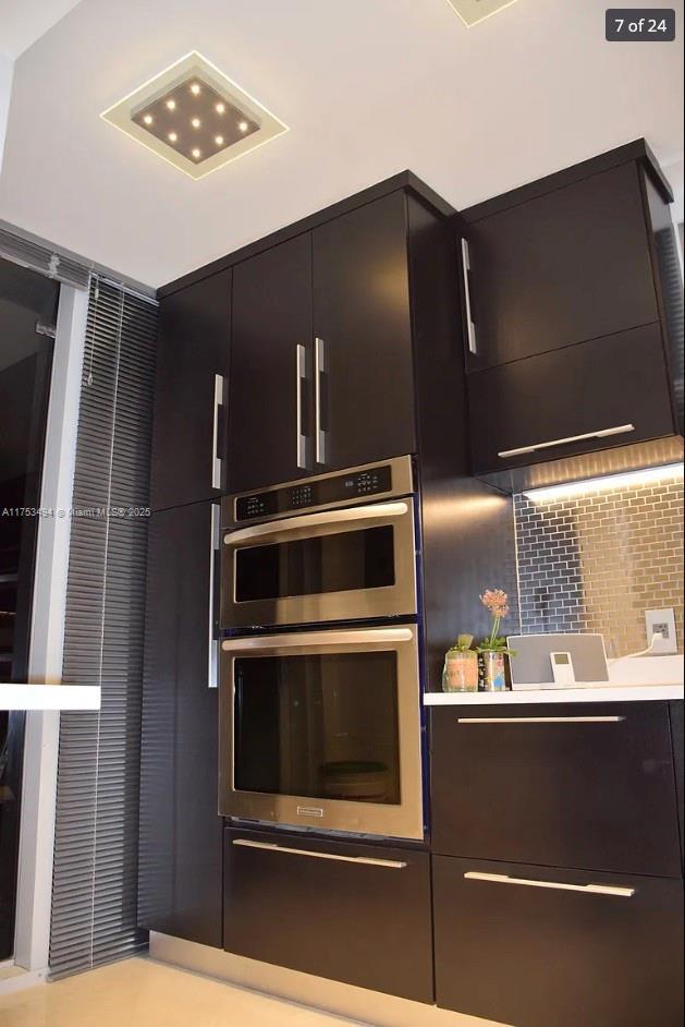 kitchen featuring stainless steel double oven, light countertops, backsplash, and modern cabinets