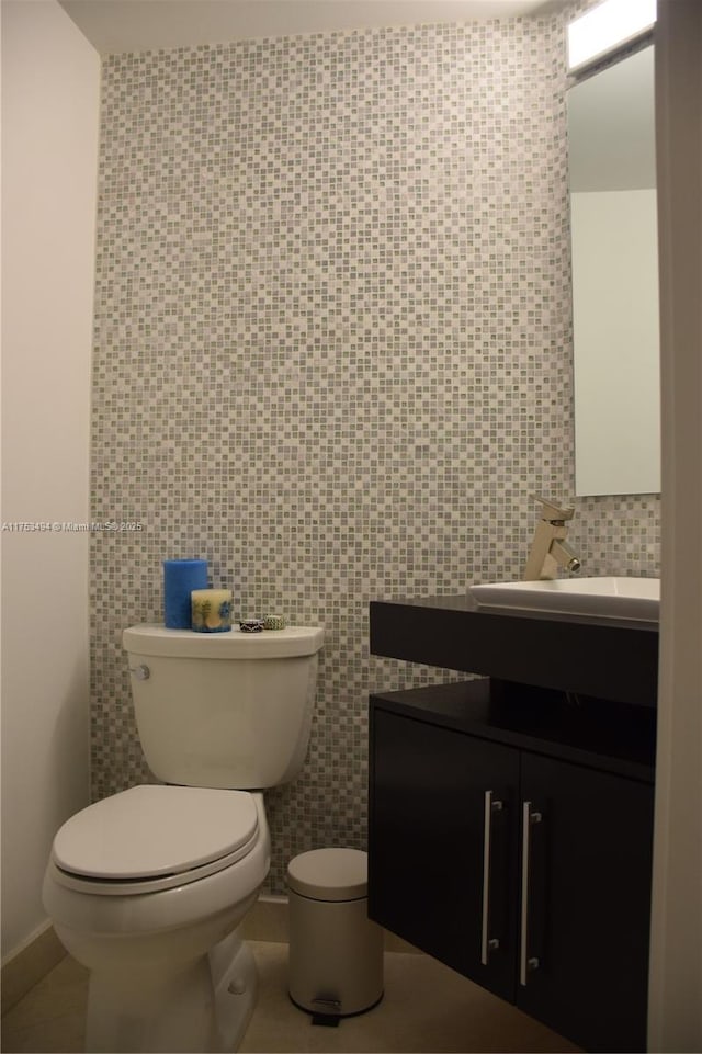 bathroom featuring toilet, tile patterned flooring, vanity, and tile walls