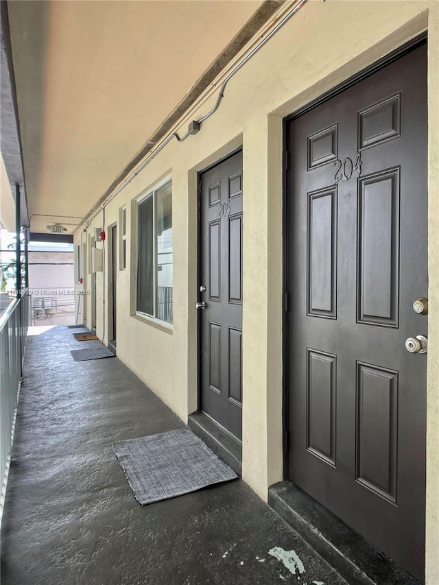 doorway to property featuring a porch and stucco siding