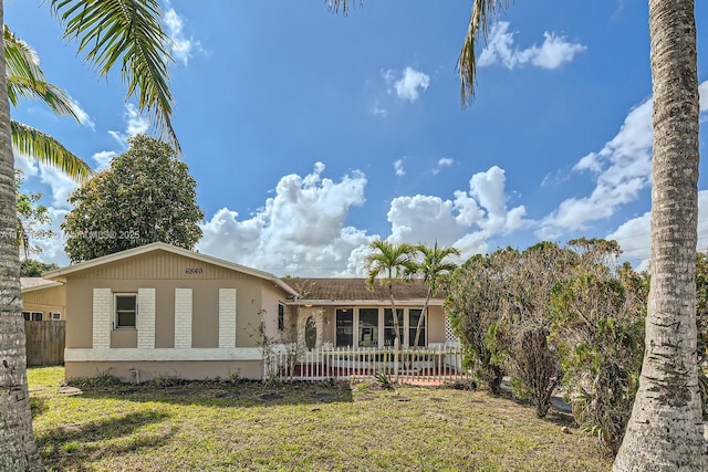 rear view of property featuring a yard, brick siding, and fence