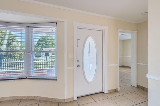 entryway with crown molding, baseboards, and light tile patterned floors