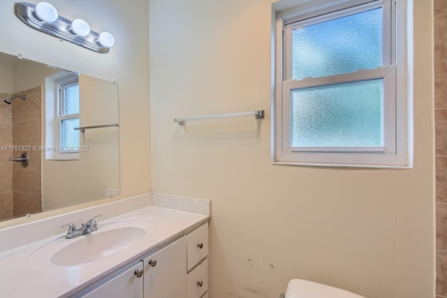 full bath with toilet, a tile shower, and vanity