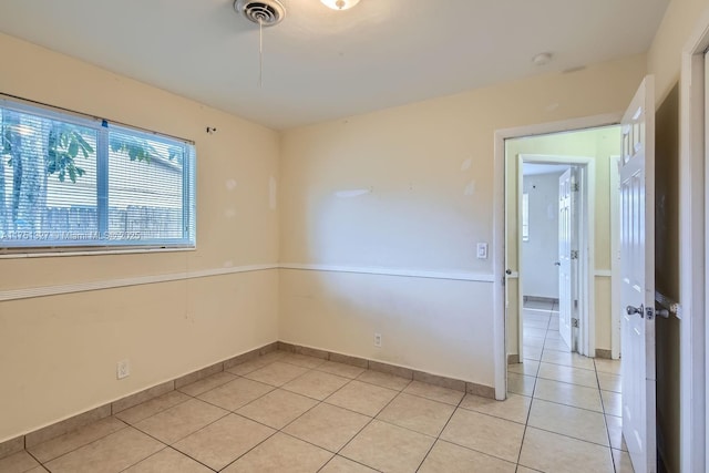 spare room featuring light tile patterned flooring, visible vents, and baseboards