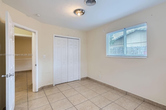 unfurnished bedroom featuring a closet, visible vents, baseboards, and light tile patterned flooring