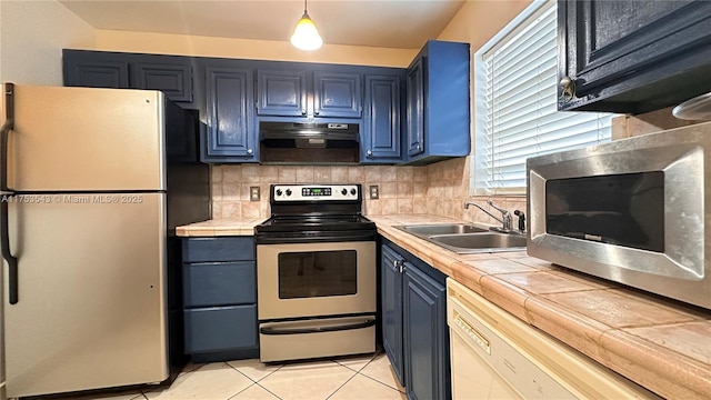 kitchen featuring tile counters, appliances with stainless steel finishes, a sink, blue cabinets, and under cabinet range hood