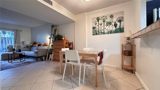 dining area with visible vents, baseboards, a textured ceiling, and light tile patterned flooring