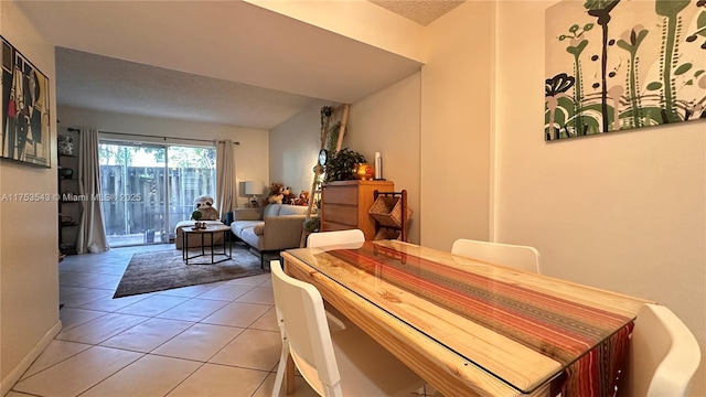 dining area featuring light tile patterned floors, a textured ceiling, and baseboards