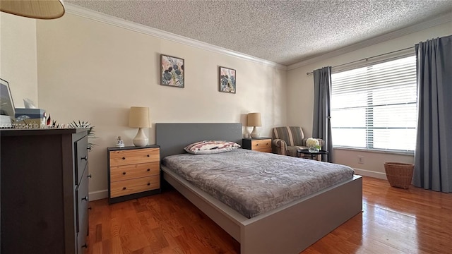 bedroom with baseboards, a textured ceiling, ornamental molding, and wood finished floors