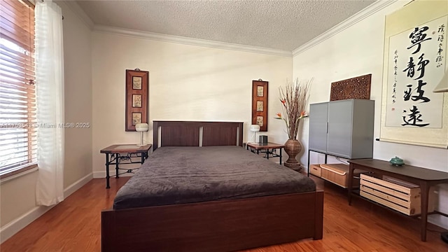 bedroom featuring a textured ceiling, ornamental molding, wood finished floors, and baseboards