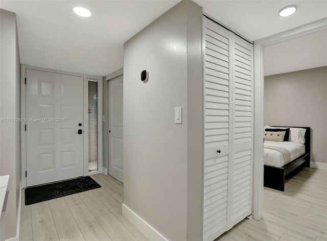 foyer entrance with light wood-style flooring, baseboards, and recessed lighting