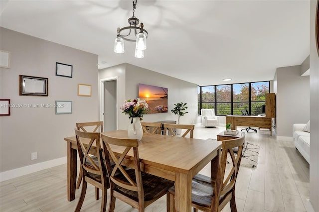 dining area with light wood-style floors, baseboards, floor to ceiling windows, and a chandelier