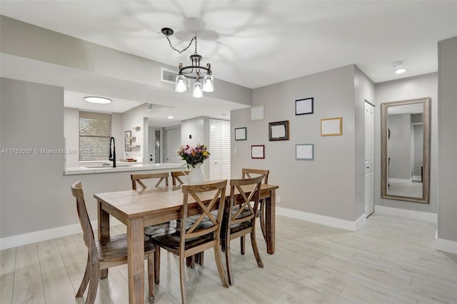 dining area featuring a notable chandelier, light wood-style flooring, and baseboards