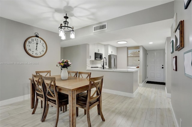 dining area with light wood-style floors, visible vents, and baseboards