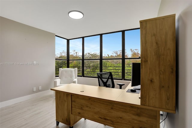 home office with light wood-type flooring and baseboards