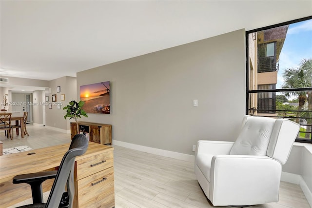 office area with light wood finished floors, visible vents, and baseboards