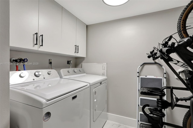 laundry area featuring marble finish floor, baseboards, washer and clothes dryer, and cabinet space