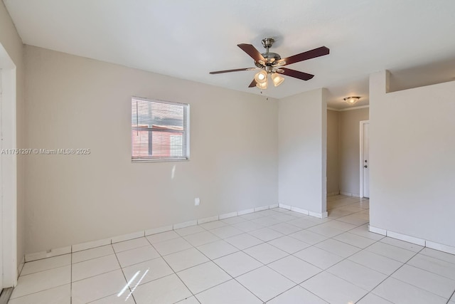 empty room featuring a ceiling fan, light tile patterned flooring, and baseboards