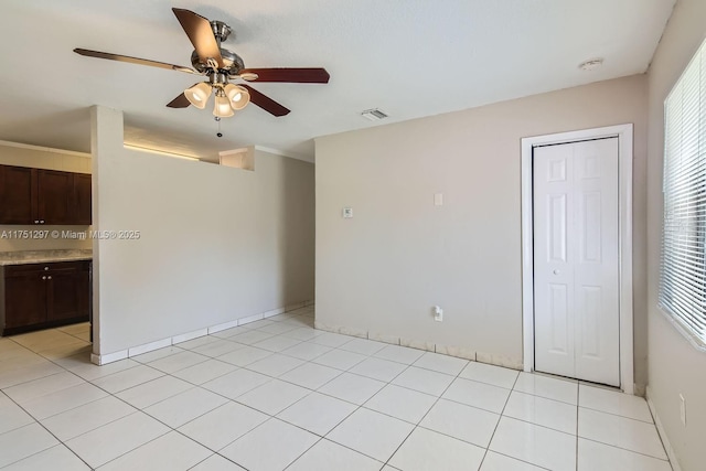 spare room featuring light tile patterned floors, plenty of natural light, visible vents, and a ceiling fan